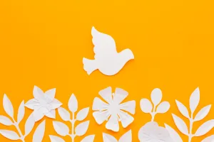 White paper-cut bird in flight above a row of white paper flowers on an orange background.
