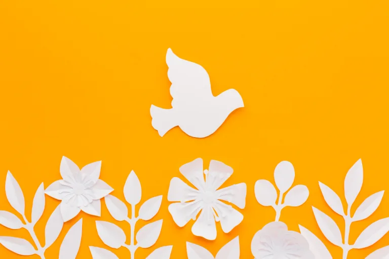 White paper-cut bird in flight above a row of white paper flowers on an orange background.